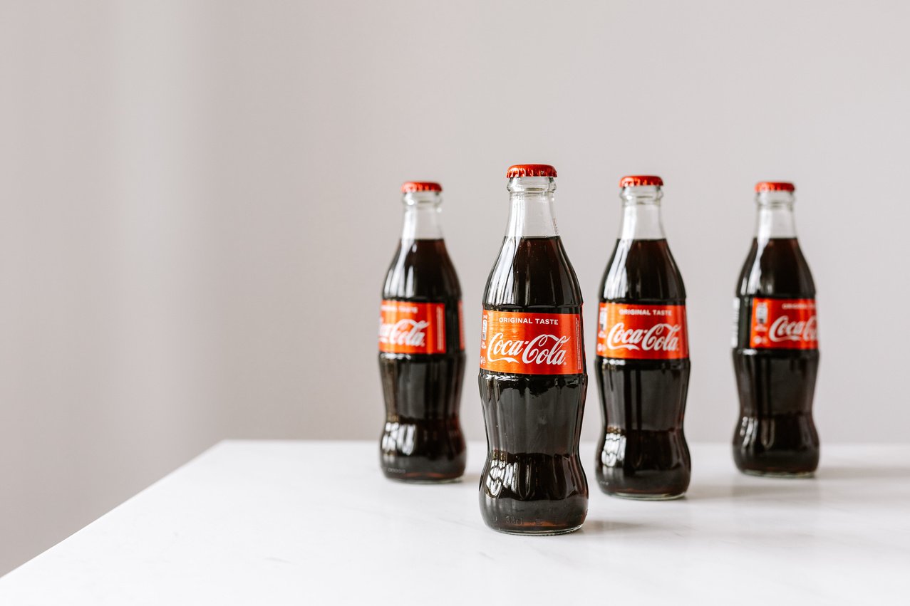 Bottles full of soft drink on white table