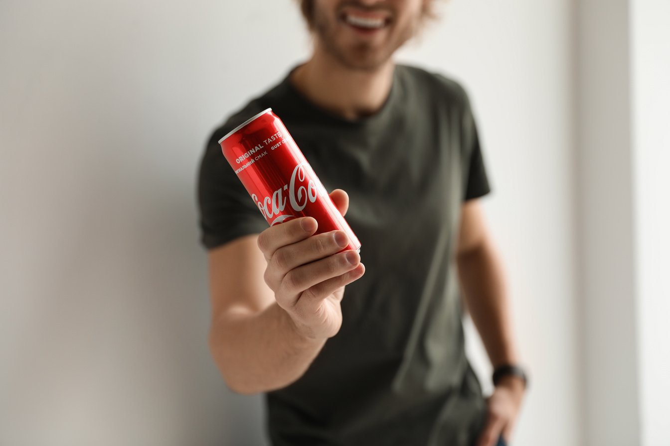 MYKOLAIV, UKRAINE - NOVEMBER 28, 2018: Young Man with Coca-Cola Can Indoors, Closeup